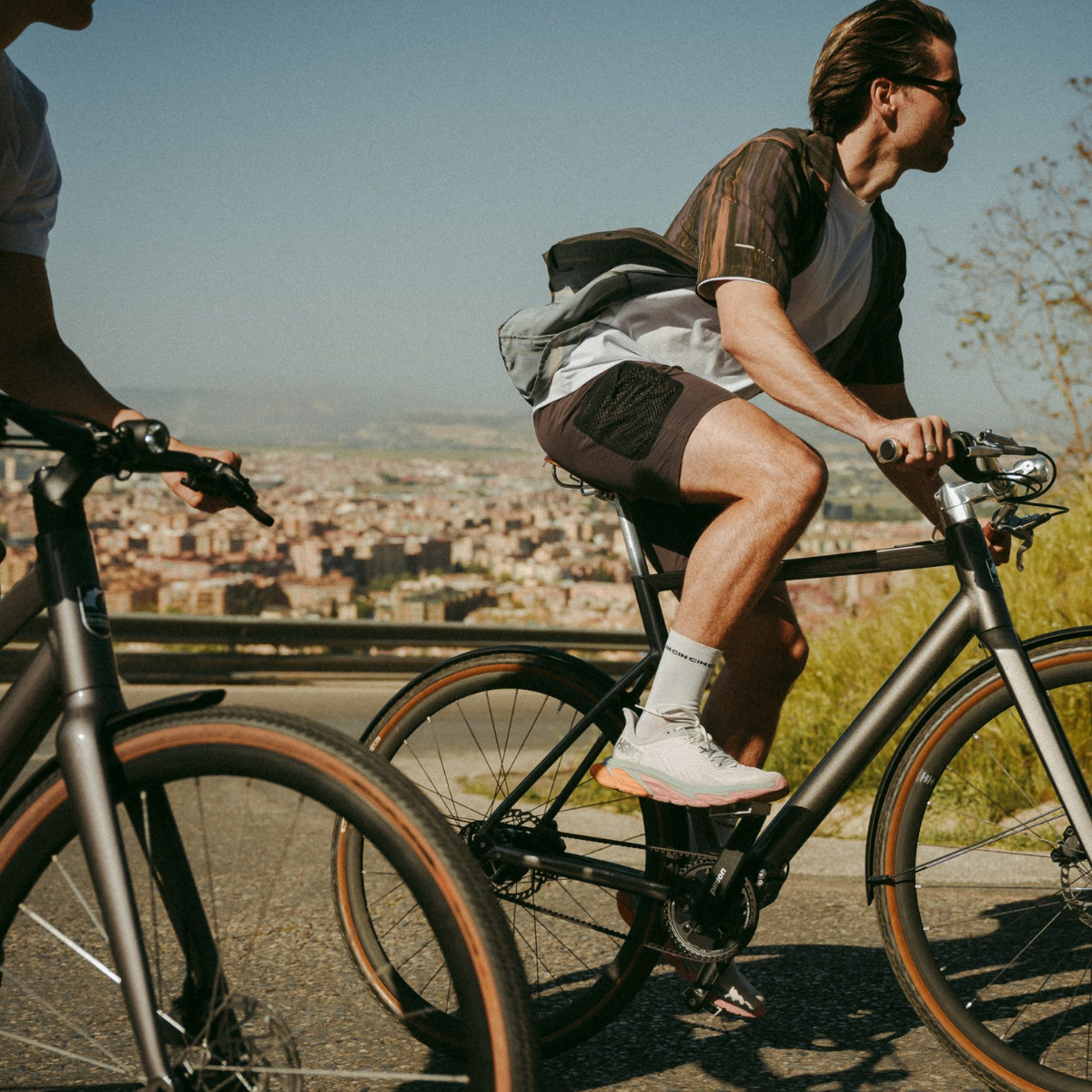 Zwei Männer fahren Desiknio-Bikes mit Blick auf die Stadt im Hintergrund.