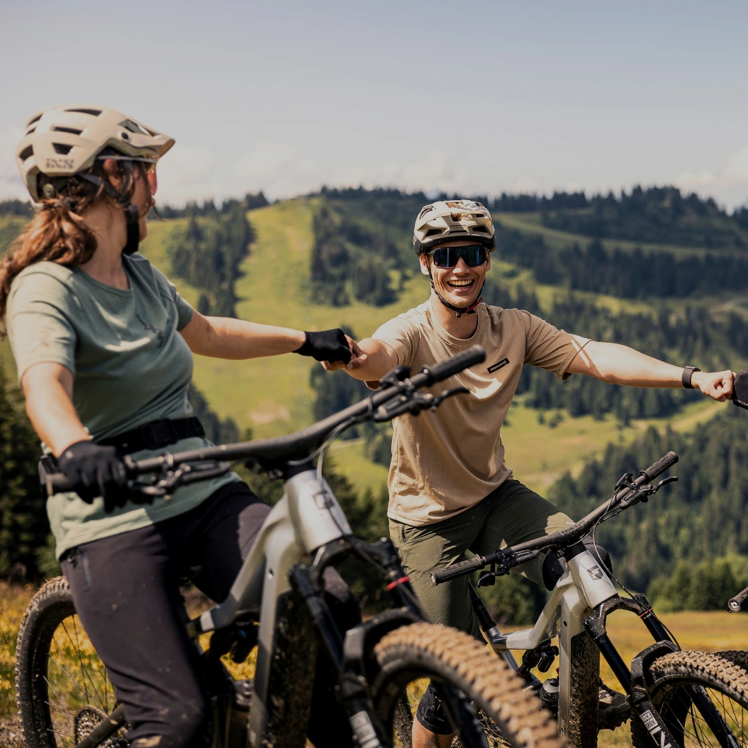 Focus E-MTB´s Gruppe von Radfahrerinnen macht eine Pause und genießt die Aussicht auf eine Hügellandschaft.