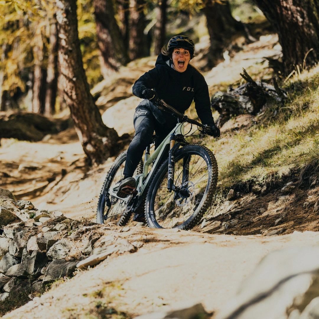 SCOR E-MTB´s Fahrer meistert eine Holzbrücke auf einem Trail durch den herbstlichen Wald.